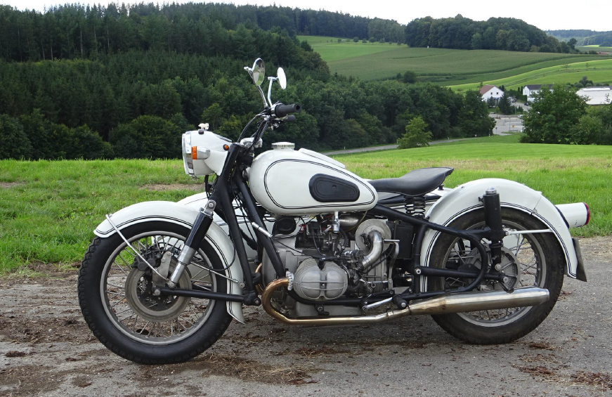 1. Ein Motorrad mit Beiwagen, das auf einer Schotterstraße inmitten von Grün geparkt ist.